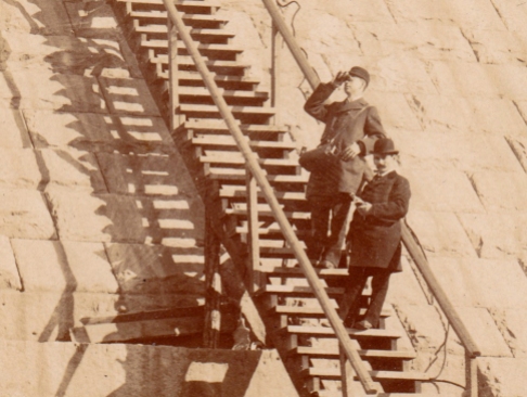 Detail showing the man higher up the stairs looking through a pair of binoculars